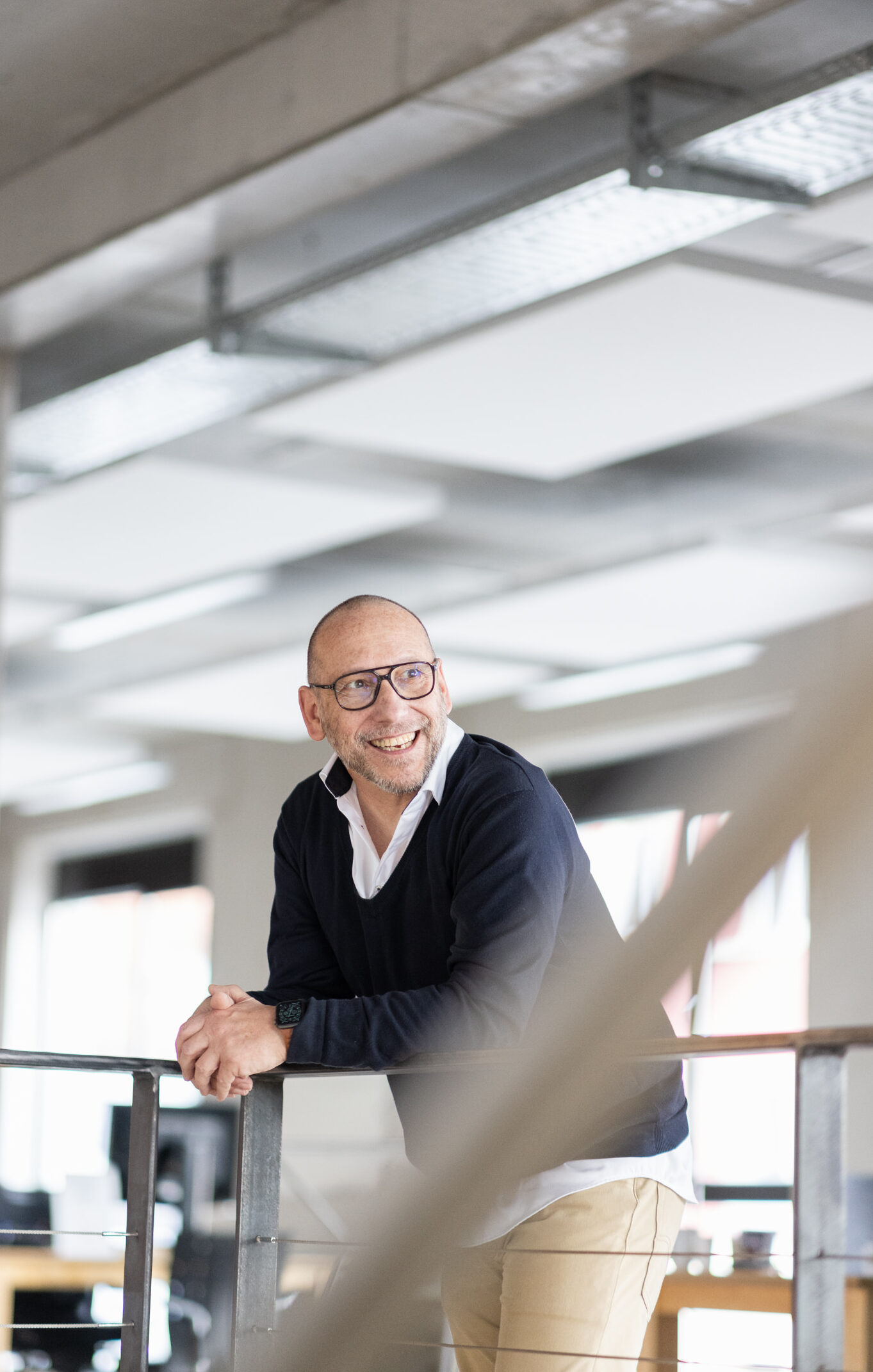 Andreas Bader, Vorstand von objective partner lehnt entspannt am Geländer im Headquarter und blickt positiv in die Ferne.