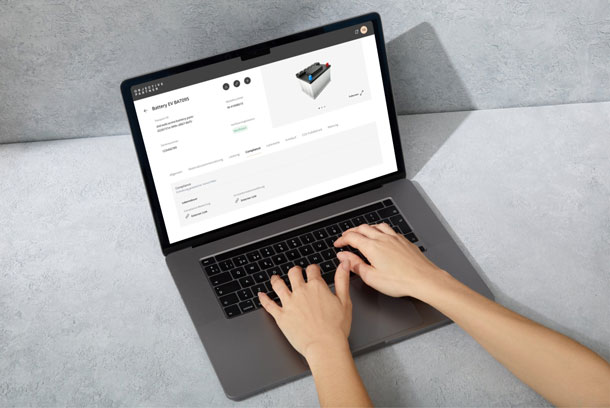 Person arbeitet an einem Laptop, der eine Asset Administration Shell für eine Batterie zeigt, mit Informationen zur Compliance und weiteren Spezifikationen, in einer modernen, minimalistischen Umgebung.